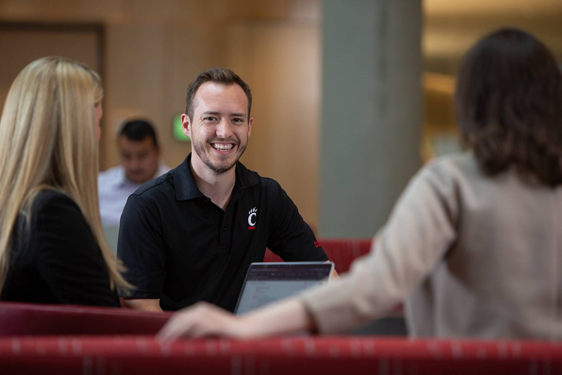 A man wearing a UC polo smiles at the camera.