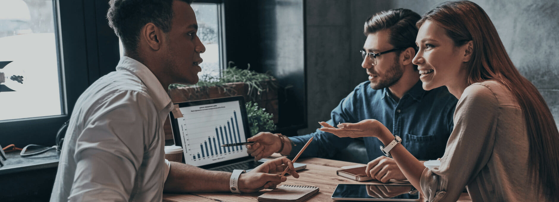 Three business accounting technology professionals discussing financial reports while looking at a laptop screen.