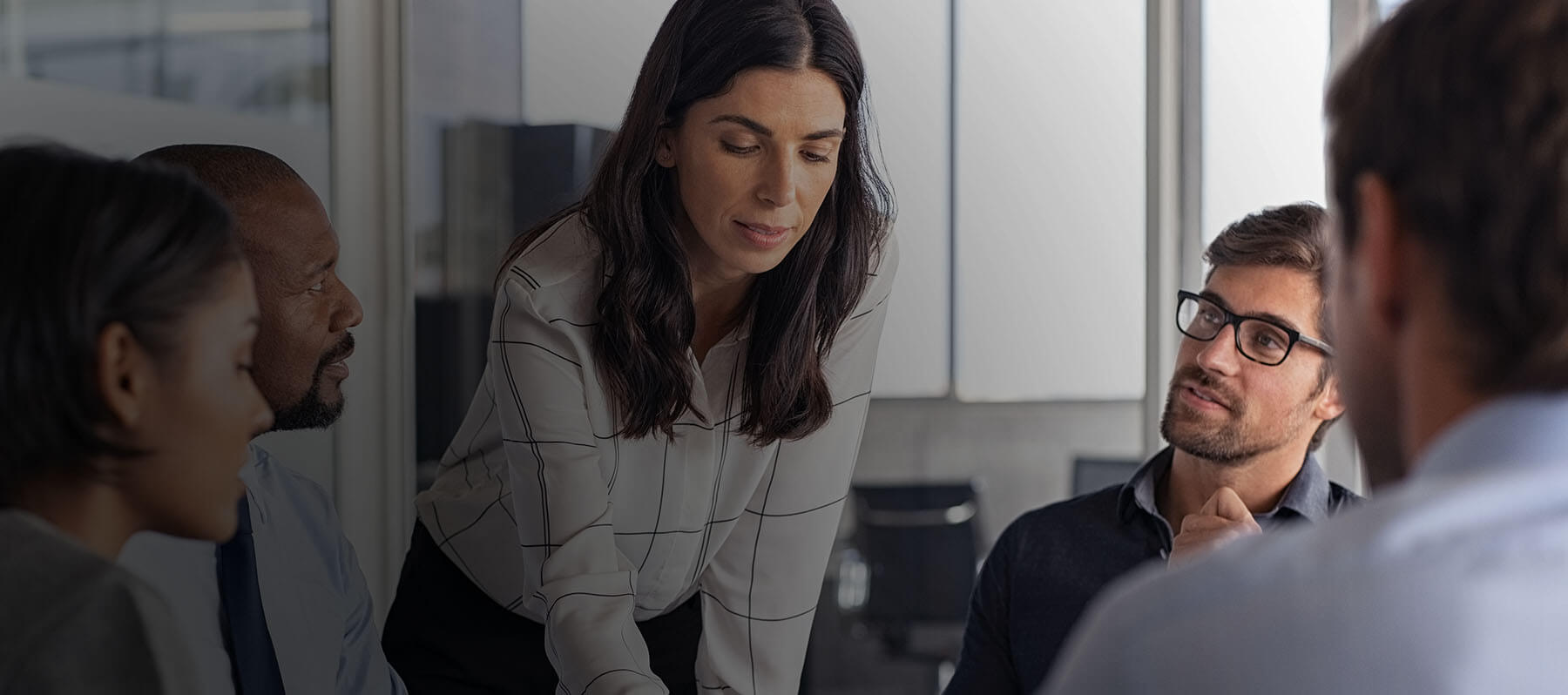 Three business accounting technology professionals discussing financial reports while looking at a laptop screen.