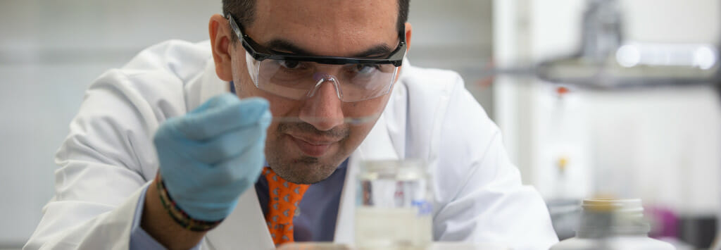 A cosmetic scientist in a lab setting examines a sample.