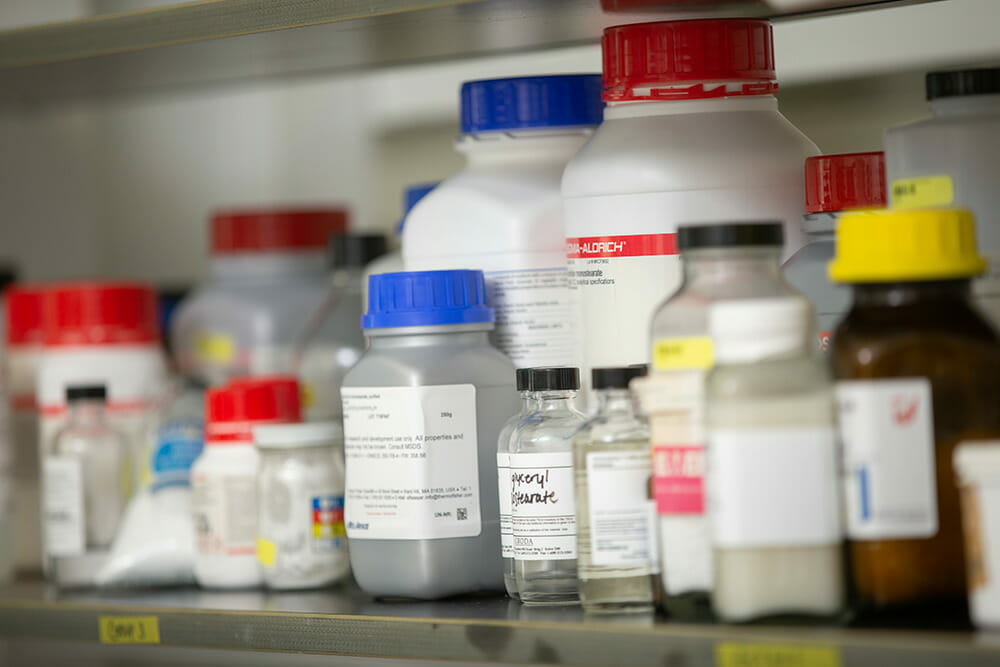 Bottles of lab chemicals and other products sitting on a shelf.