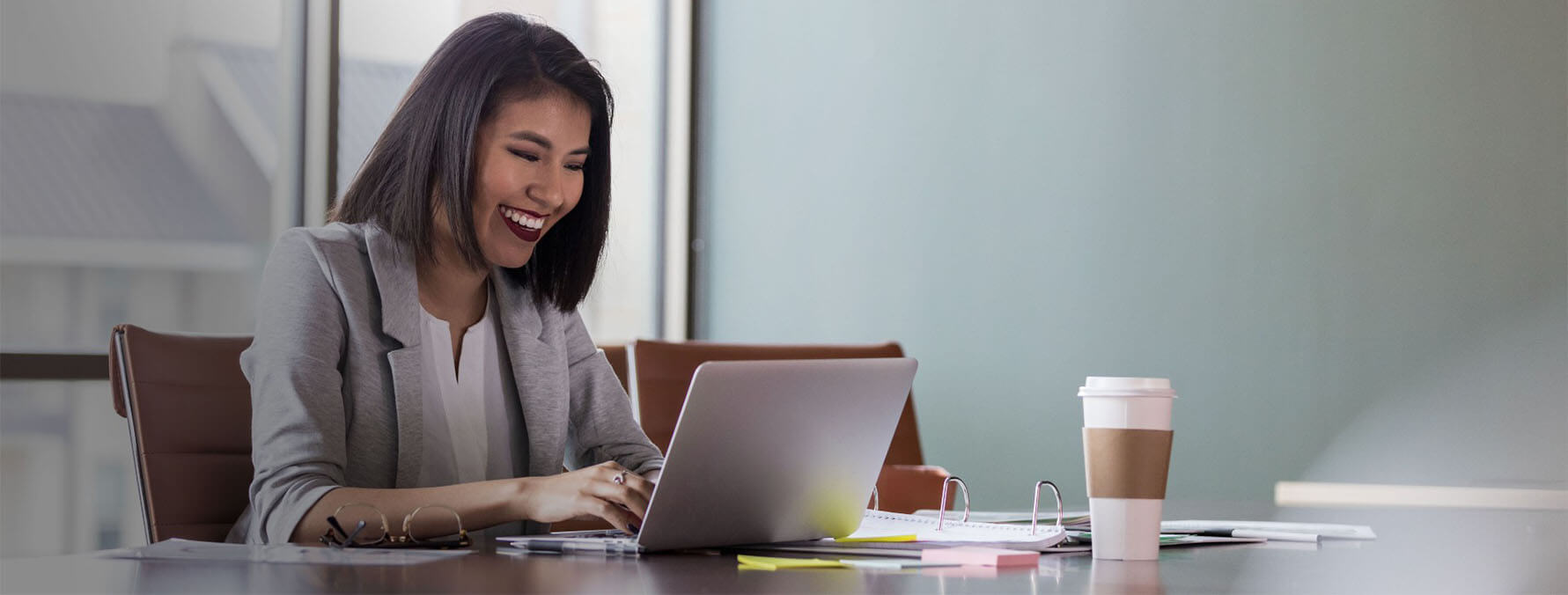 Physician practice management professional smiling at a laptop.