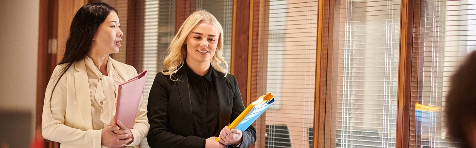 Two professionals walking down a hallway discussing legal documents, representing students in the Master of Legal Studies program.