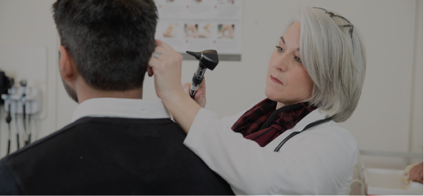 Nurse practitioner examining patient’s ear in clinical setting.