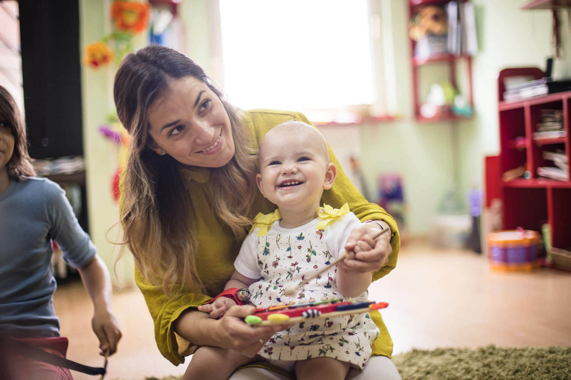 Infant playing music with teacher