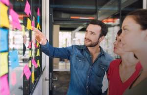 Marketing Graduate student pointing to sticky note in hallway