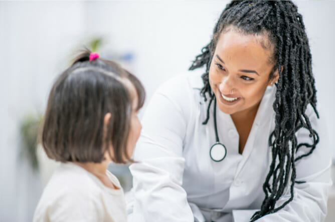 Family Nurse Practitioner examining pediatrics ear with auriscope