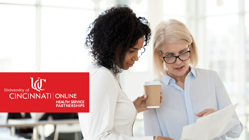 Two women standing looking at a document
