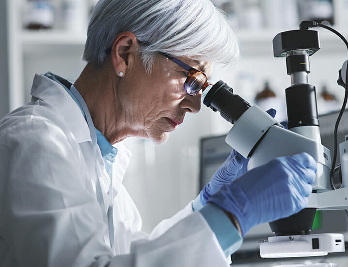 woman in lab looking into a microscope