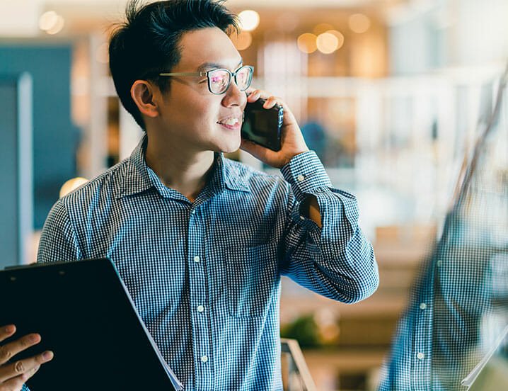 person talking on phone holding binder