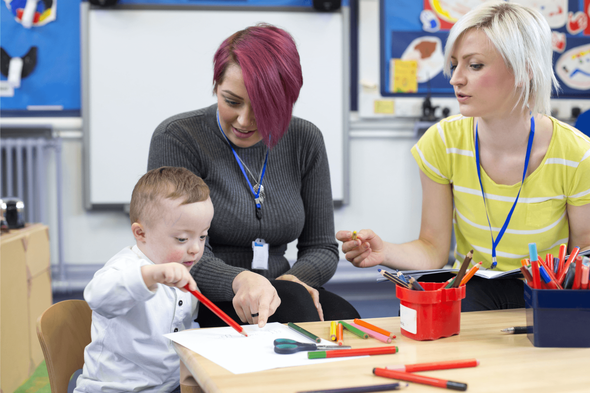 Two female teachers coloring with child
