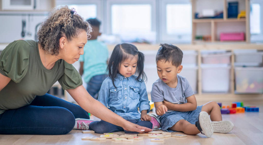 female teacher instructing two toddlers