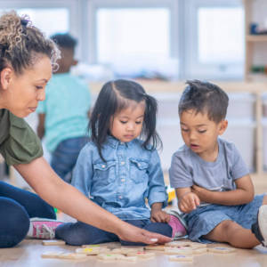 female teacher instructing two toddlers