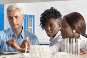 A laboratory leader listens to the reports from his two African American female laboratory techs
