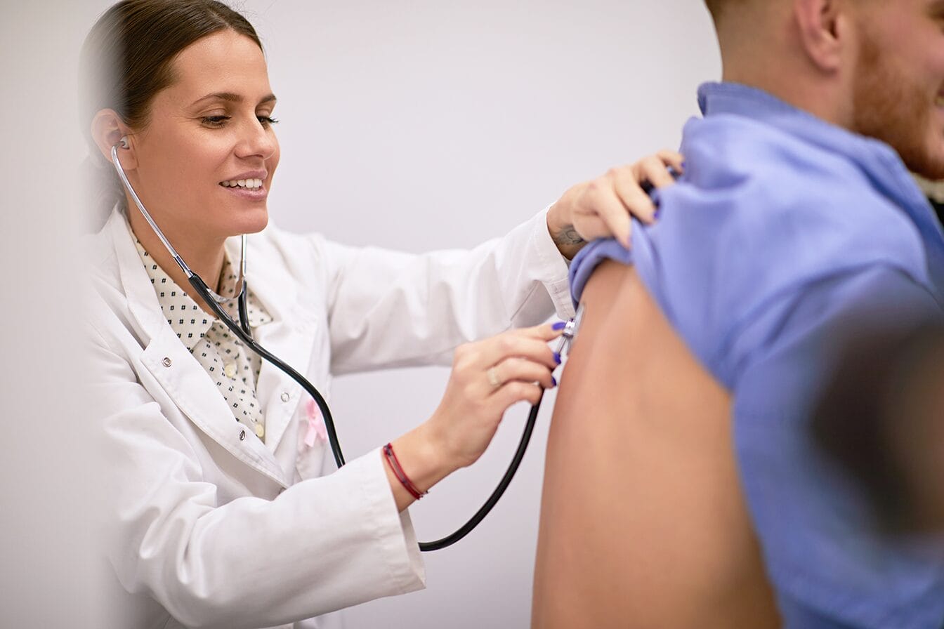 A respiratory therapist monitoring a patient's breathing through a stethoscope